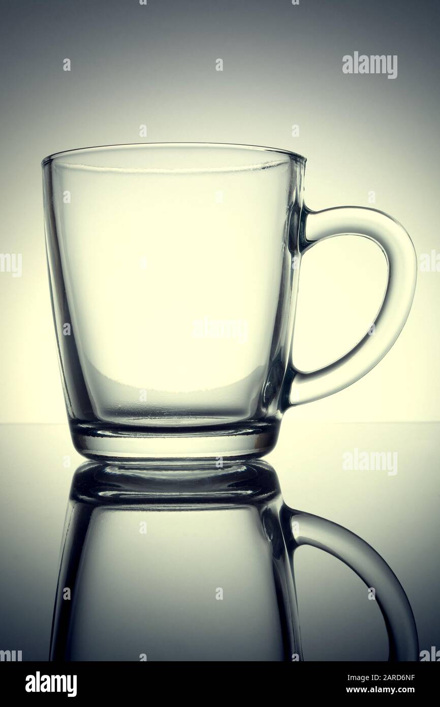 Tazza trasparente con riflessione su sfondo grigio. Vecchia foto vintage retrò stile grunge. Foto Stock