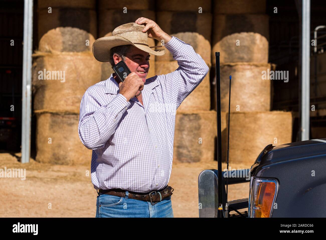 Farmer sul telefono cellulare toccando cappello vicino al camion con due antenne Foto Stock