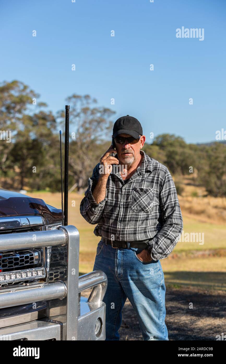 Uomo su telefono cellulare con vista paddock, accanto alla parte anteriore del camion con antenne Foto Stock