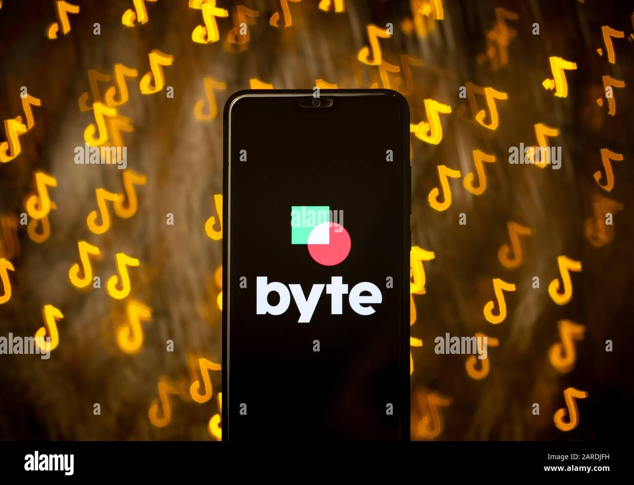 Byte app logo sullo smartphone e bokeh in una forma di TikTok logo sullo sfondo. Non un montaggio. Nessuna modifica di foto. Viene utilizzata la tecnica di forma bokeh personalizzata. Foto Stock
