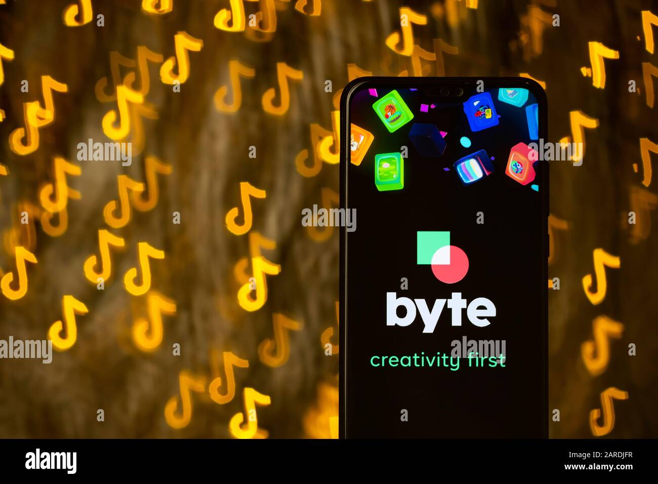 Byte app logo sullo smartphone e bokeh in una forma di TikTok logo sullo sfondo. Non un montaggio. Nessuna modifica di foto. Viene utilizzata la tecnica di forma bokeh personalizzata. Foto Stock