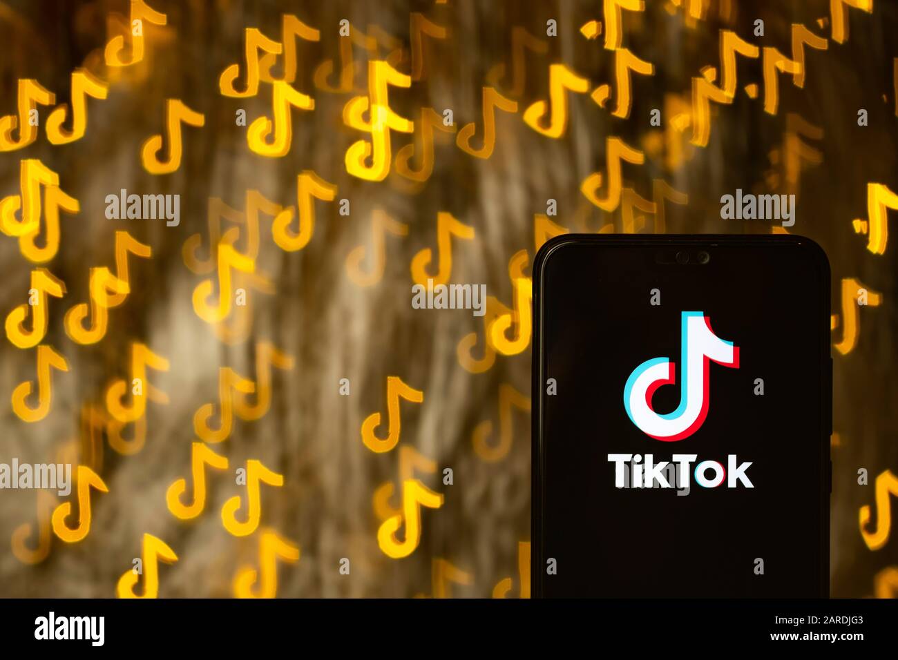 TikTok app logo sullo smartphone e bokeh in una forma di TikTok sullo sfondo. Non un montaggio. Nessuna modifica di foto. Viene utilizzata la tecnica di forma bokeh personalizzata. Foto Stock