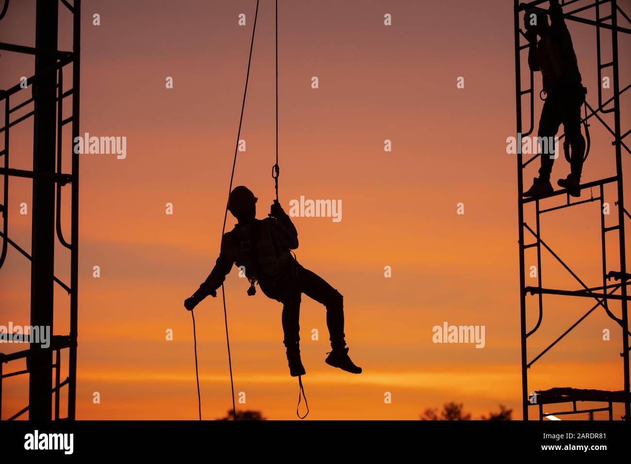 Silhouette Construction site Engineers sono in corda doppia con zip line. Foto Stock