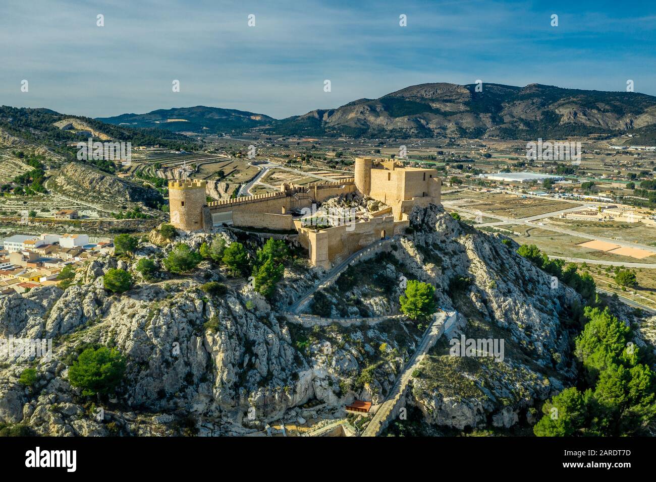 Veduta aerea del castello di Castalla, nella provincia di Valencia, Spagna, con il suo mastio che domina la città e un cortile rinforzato da una torre circolare al sole Foto Stock