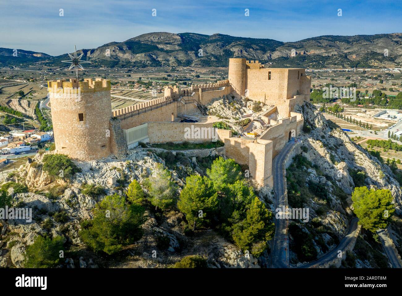 Veduta aerea del castello di Castalla, nella provincia di Valencia, Spagna, con il suo mastio che domina la città e un cortile rinforzato da una torre circolare al sole Foto Stock