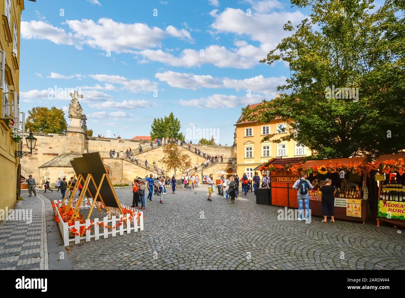 I turisti godono di una giornata di sole nella piazza del mercato con scale che collegano l'Isola di Kampa al Ponte Carlo a Praga, Repubblica Ceca Foto Stock