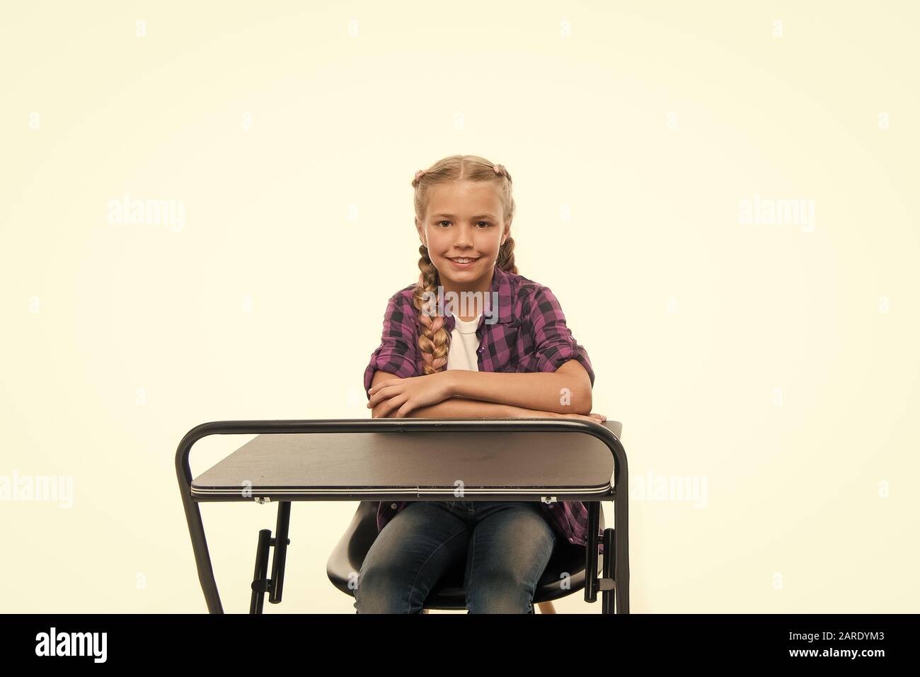 Si torna a scuola. Carino scuola bambino seduto alla scrivania isolato su bianco. Little Schoolgirl avente lezione nella scuola primaria. Adorabile bambina godendo della sua scuola. Foto Stock