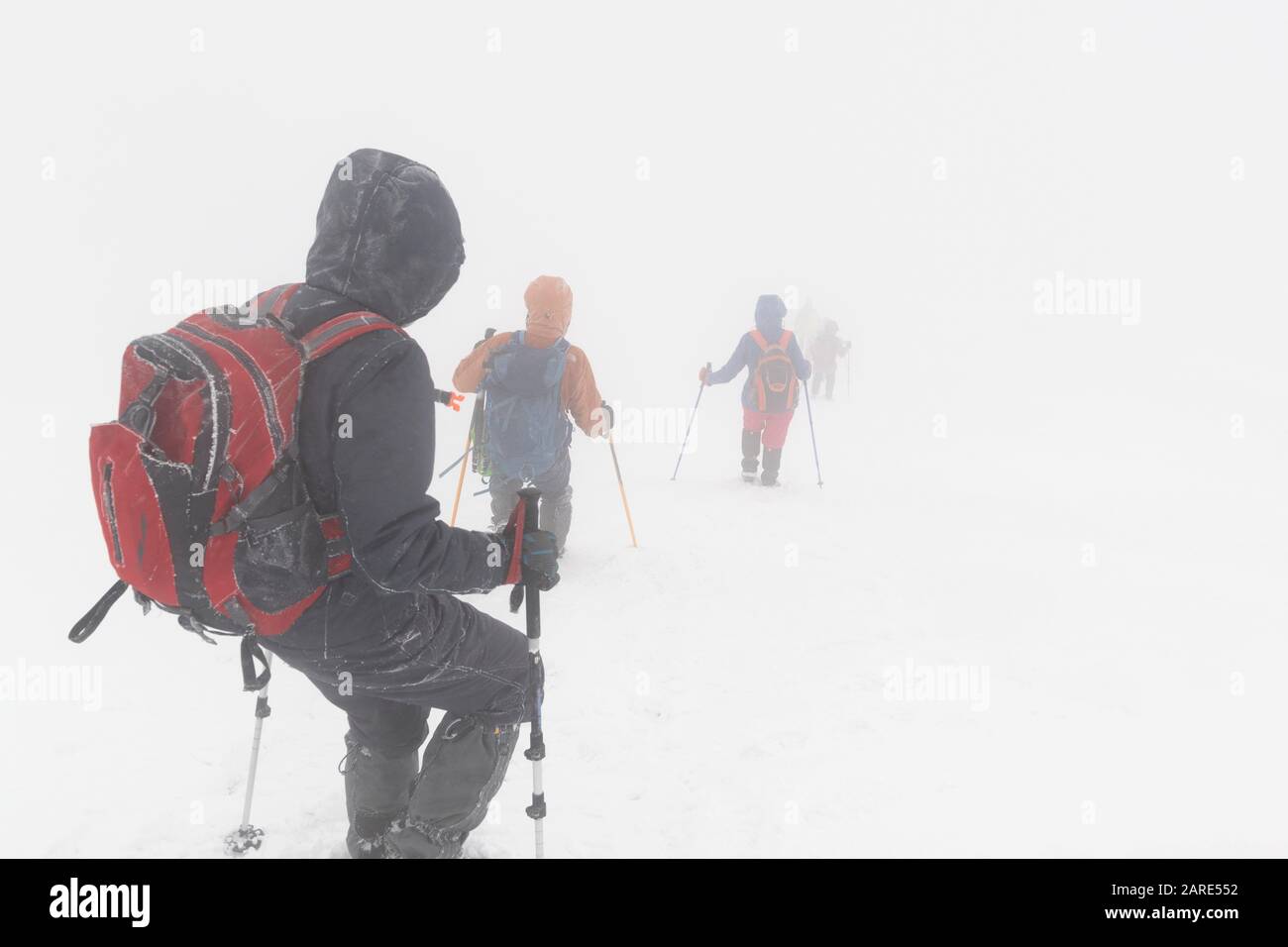 Escursionisti in montagna d'inverno in cattive condizioni atmosferiche e scarsa visibilità Foto Stock