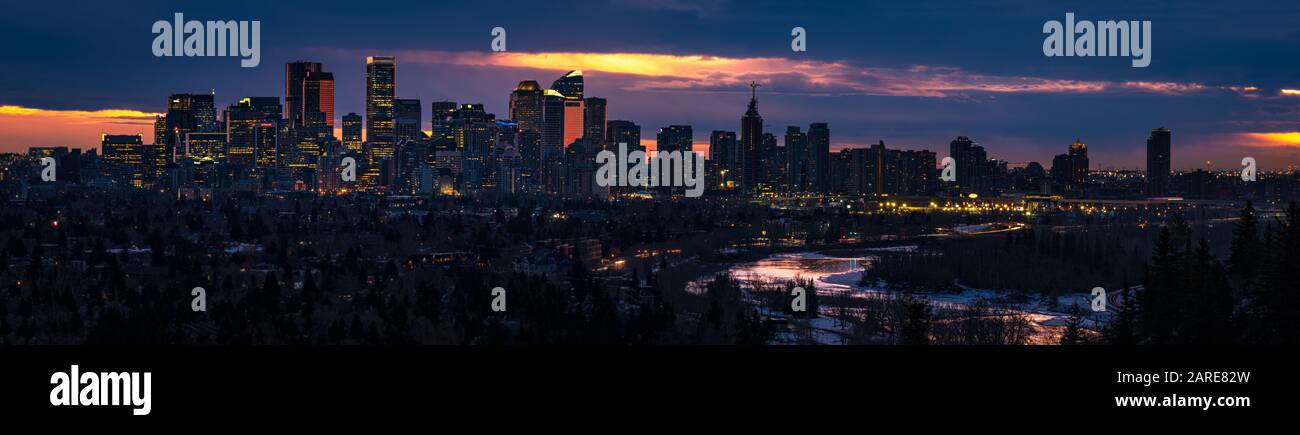Vista panoramica della città di Calgary durante l'alba. Tempesta nuvole all'orizzonte e grattacieli che sono incandescenti. Foto Stock