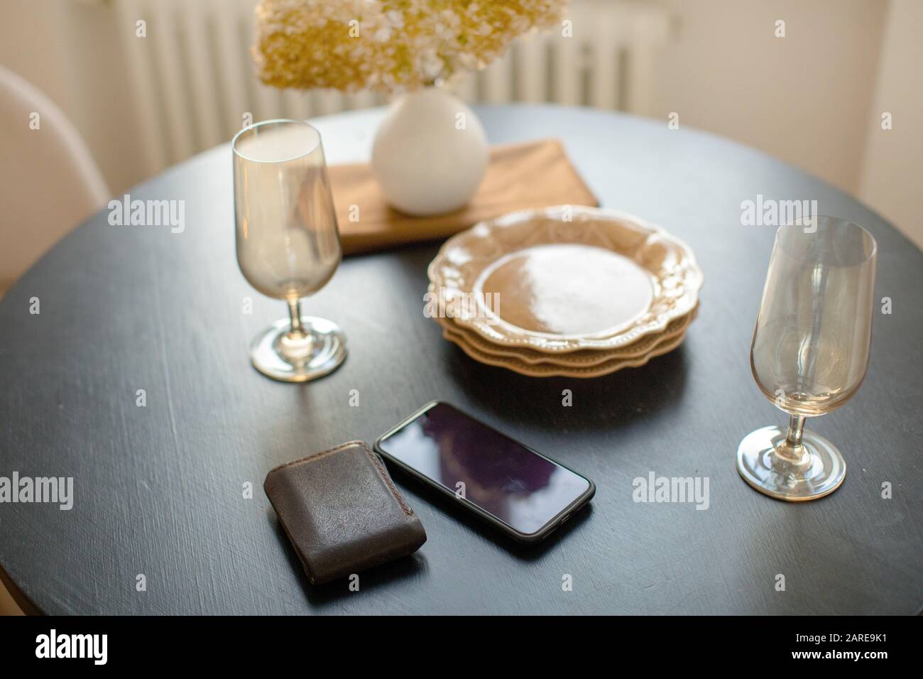 Smartphone con stoviglie e portafoglio sul tavolo decorato con vaso di fiori Foto Stock