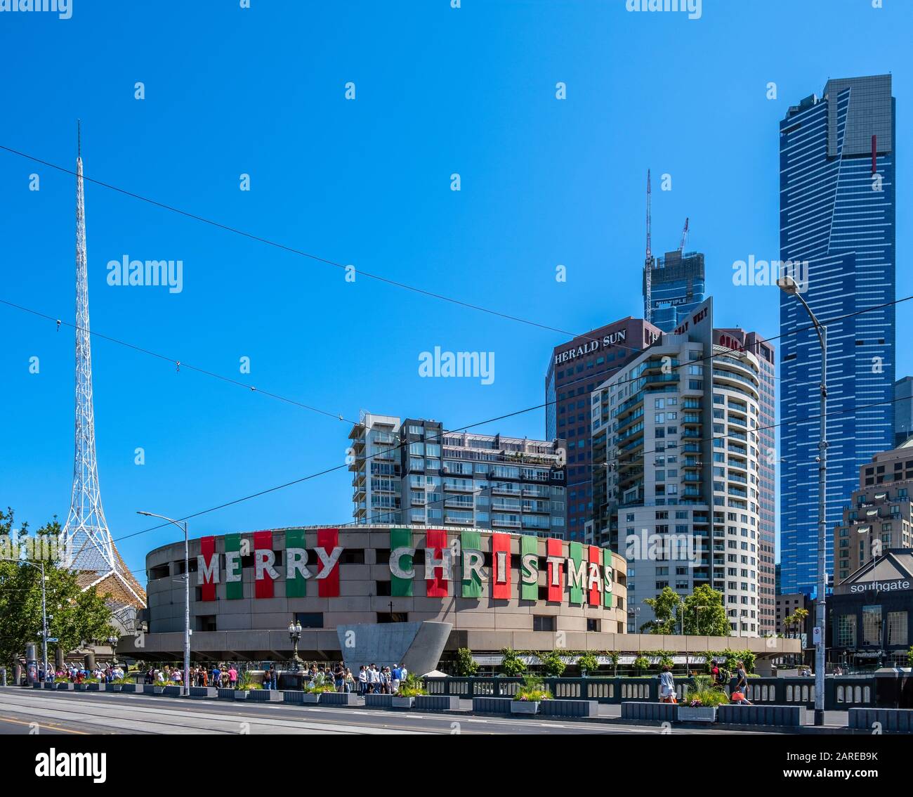 Melbourne, Australia - Circa Dicembre, 2019: Arts Center esterno decorato con buon testo di Natale in una luminosa giornata di sole con persone che camminano su Saint Foto Stock