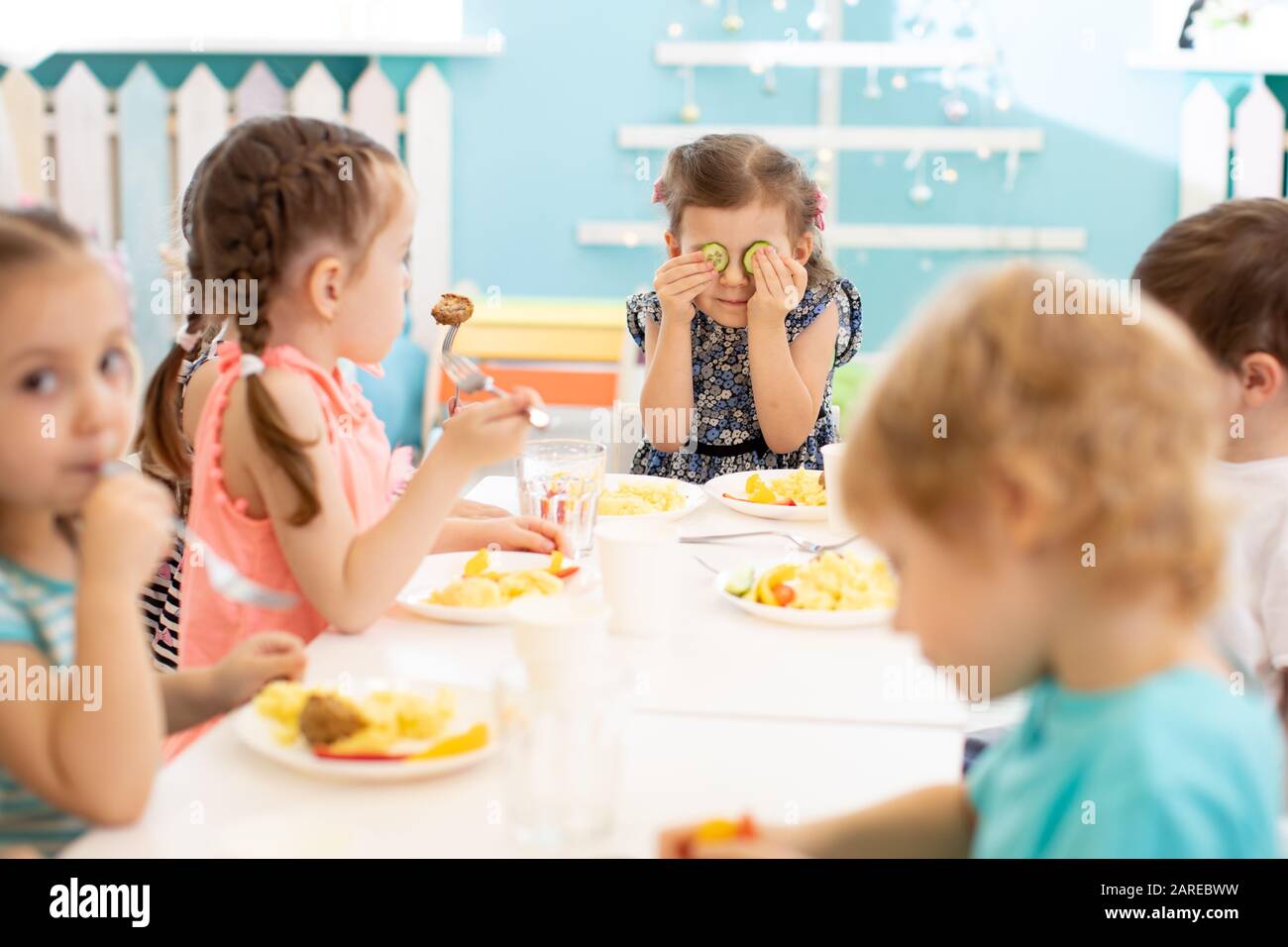 gruppo di bambini prescolare che mangiano da piatti nel centro di cura di giorno Foto Stock