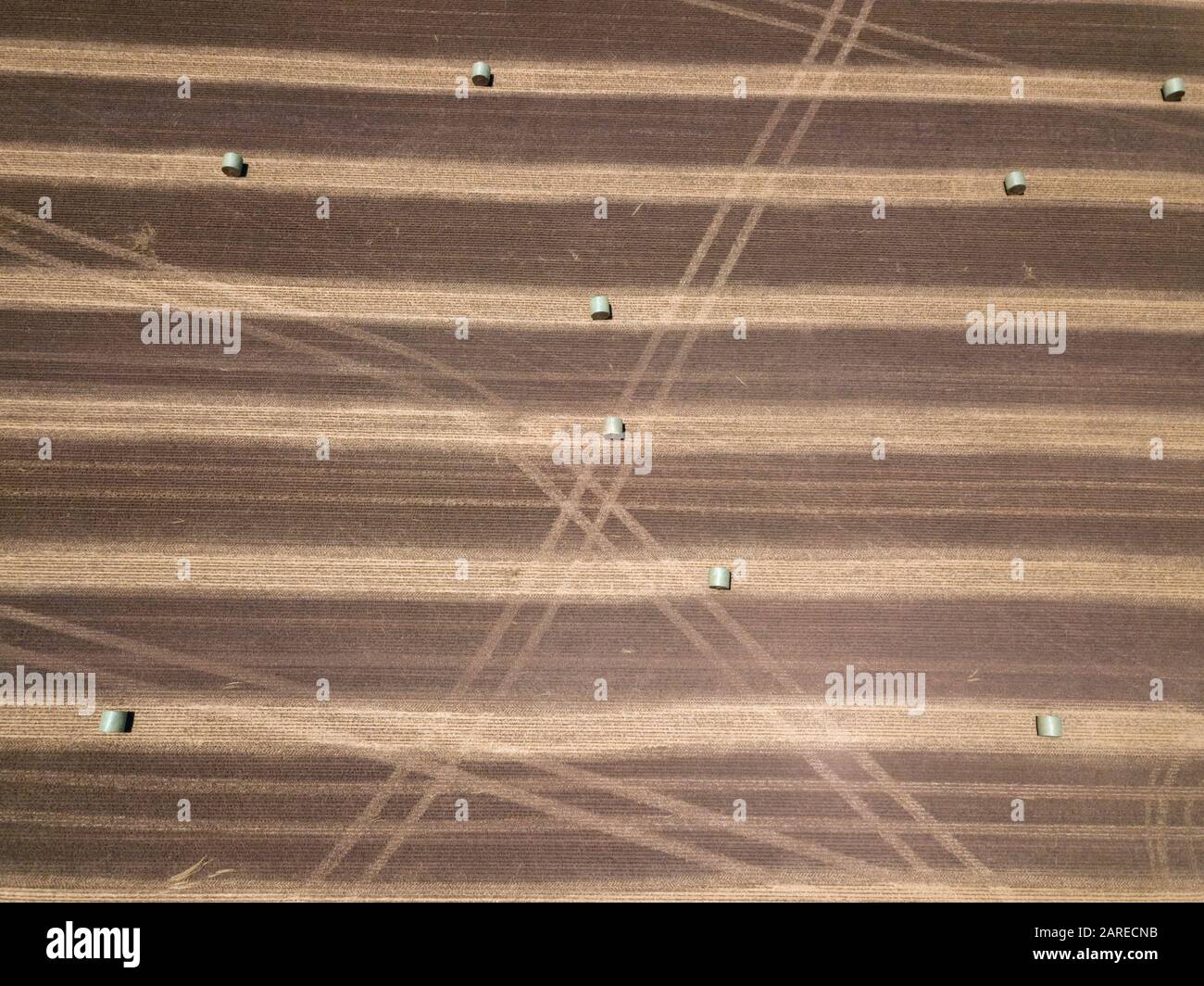 Paddock agricolo con balle di fieno rotonde, piste e motivi astratti di fondo, vista aerea, Victoria, Australia Foto Stock