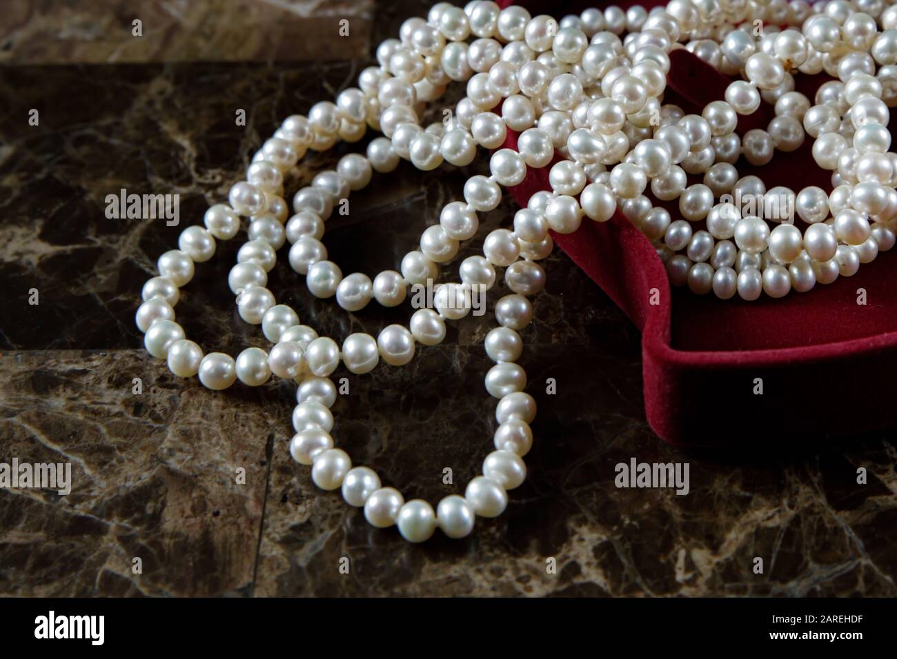 Collana di perle in una scatola regalo rossa a forma di cuore su sfondo  marmoreo. Primo piano. Buon compleanno o giorno della madre. Un regalo  romantico per San Valentino o Foto stock -