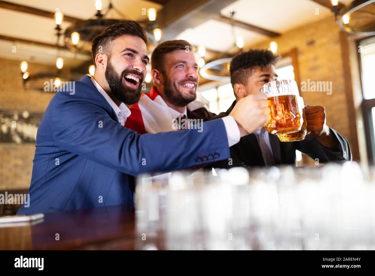 Vecchi amici allegri che si divertono e bevono birra al banco bar nel pub. Foto Stock