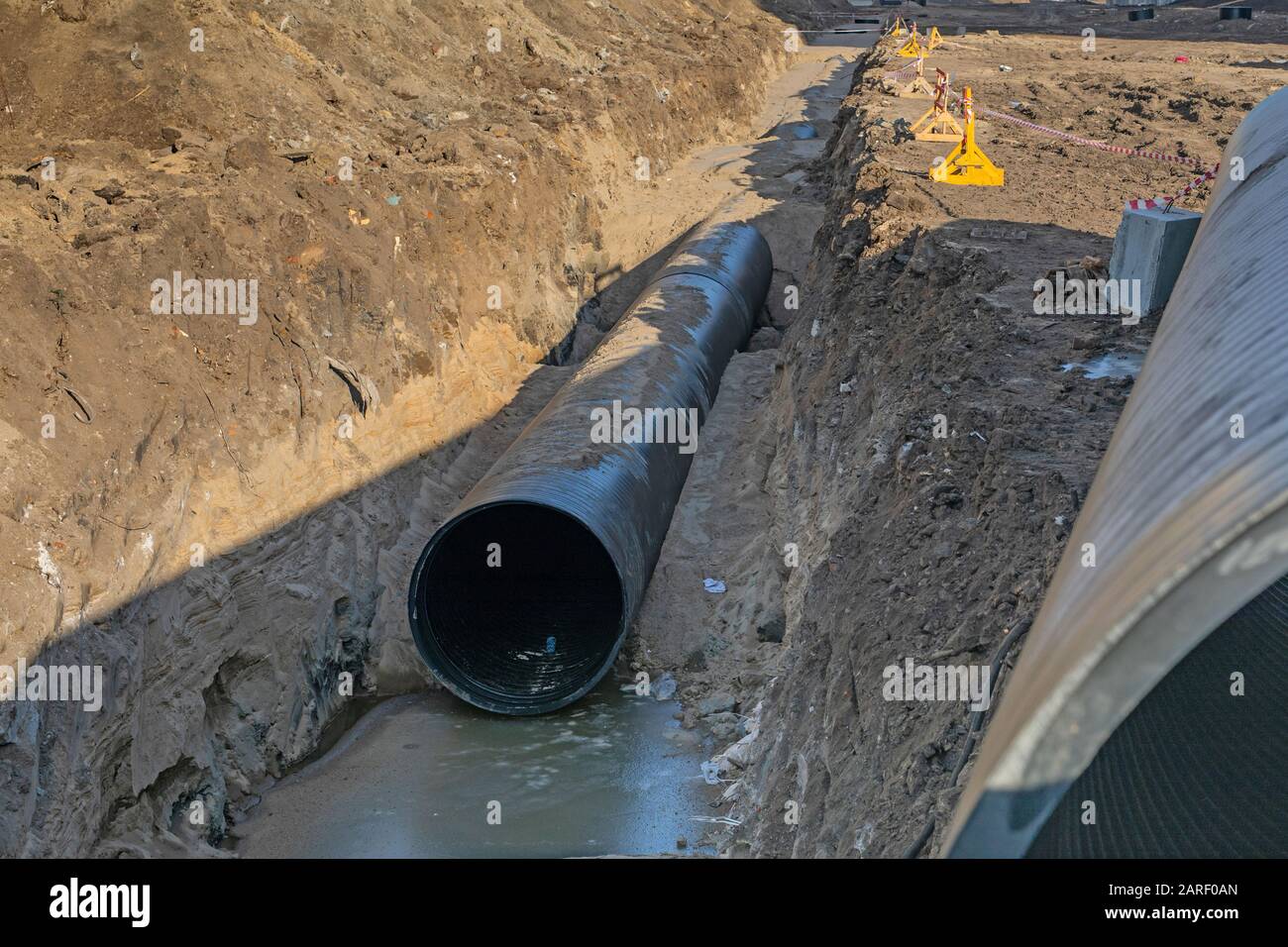 processo di posa di impianti tecnici e di riscaldamento. tubi in plastica nera sono in trincea di terra. Foto Stock