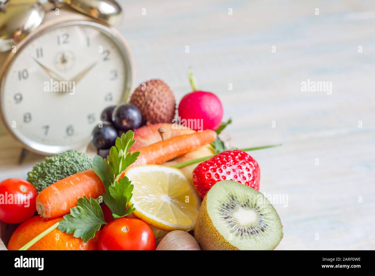 Time on dieta e sano stile di vita con frutta e verdura e sveglia Foto Stock