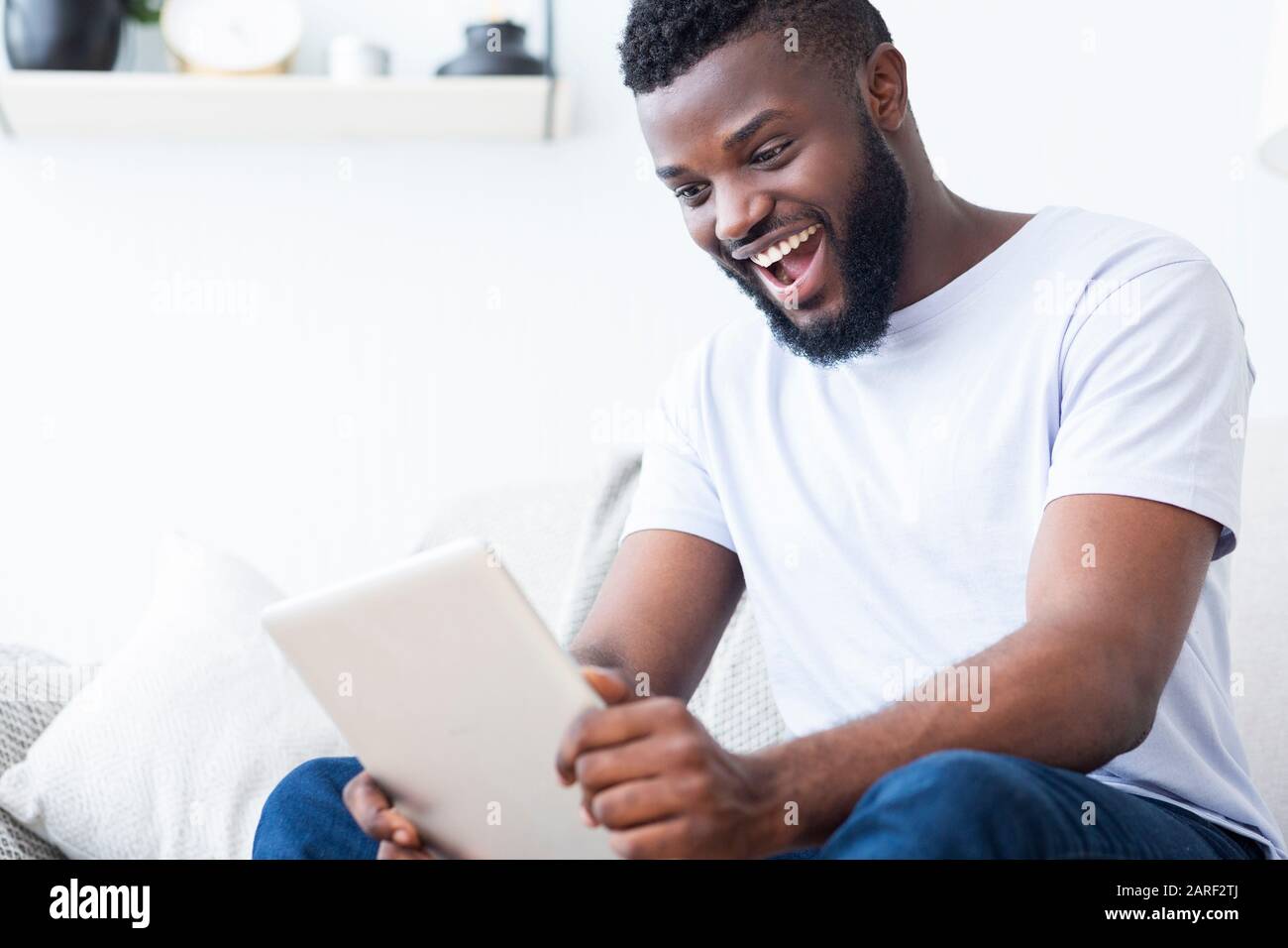 Fan africani emotivi che guardano gli sport online su tablet digitali Foto Stock