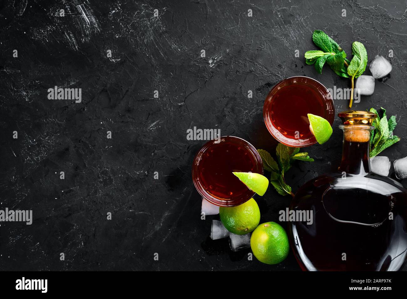 Bevande alcoliche Rum, lime e menta su sfondo di pietra nera. Vista dall'alto. Spazio libero per il testo. Foto Stock
