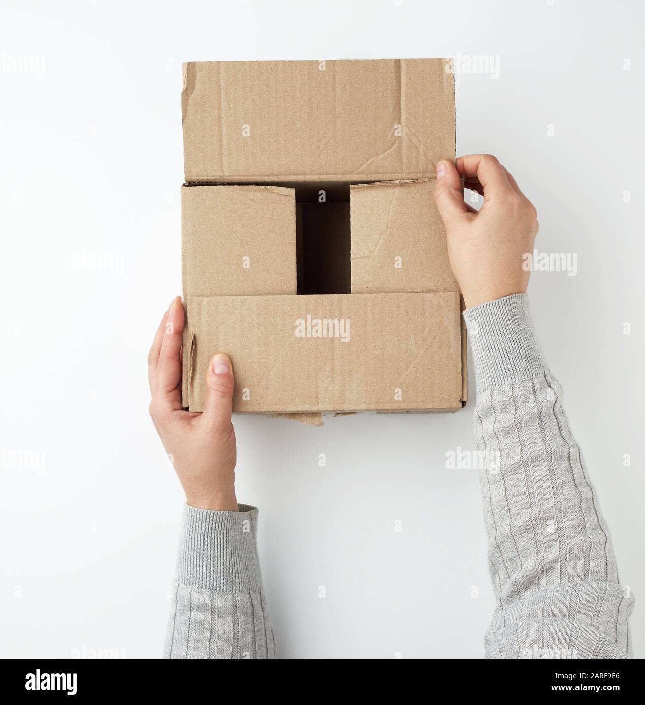 due mani femminili chiudono una scatola di cartone marrone quadrato su uno  sfondo bianco, concetto di movimento e consegna delle merci Foto stock -  Alamy