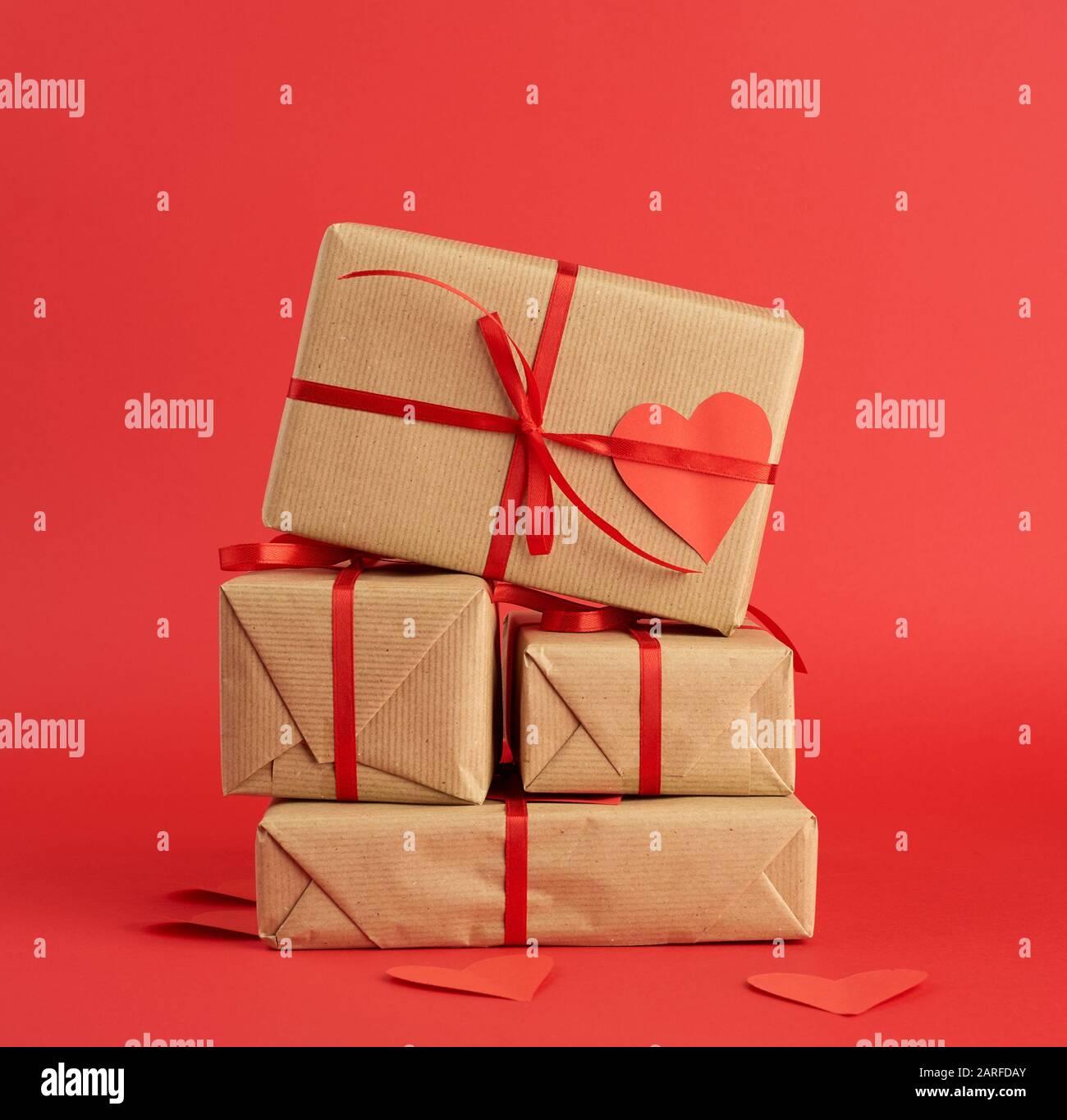 Pacco di regali confezionati in carta marrone e legato con un nastro rosso  su rosso, sorpresa e un regalo per San Valentino 14 febbraio Foto stock -  Alamy