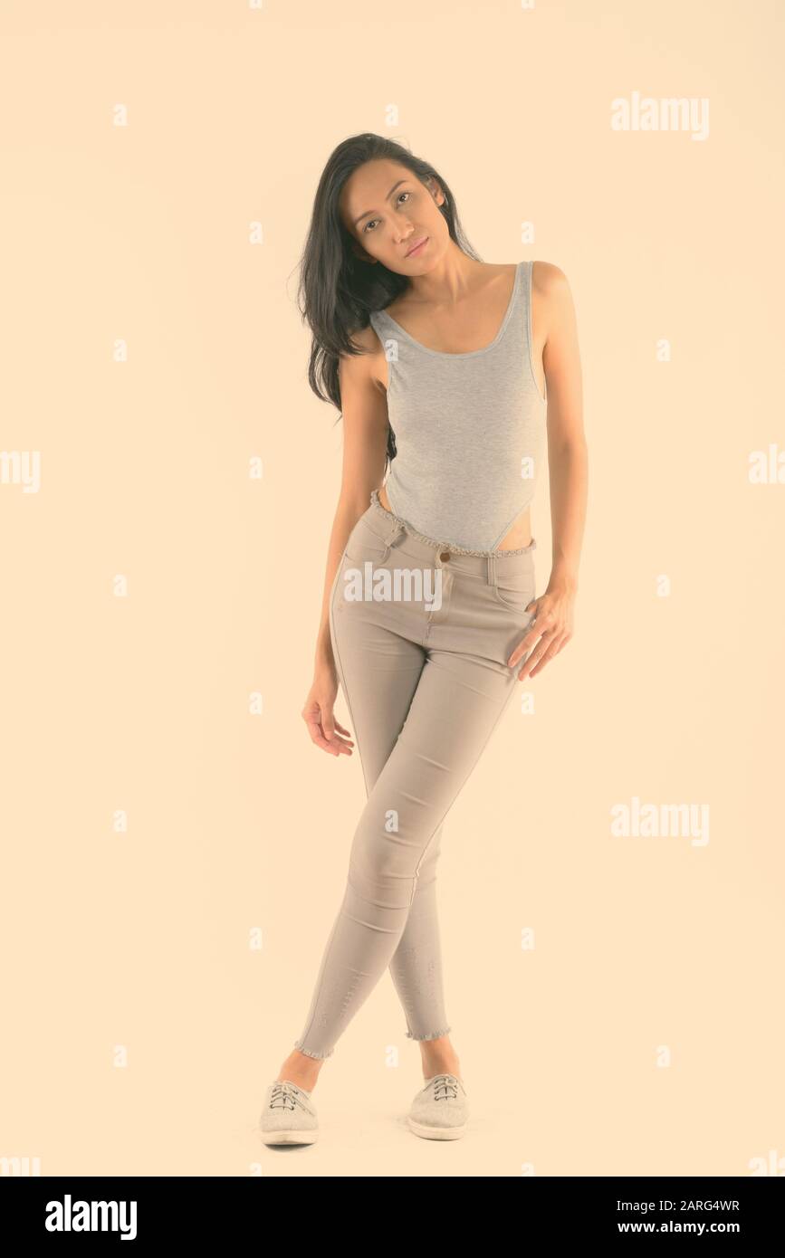 Corpo pieno colpo di giovane bella donna asiatica in piedi con i piedi attraversata Foto Stock