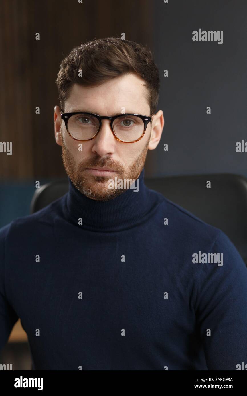 Giovane uomo d'affari in ufficio. Ritratto d'affari di bell'uomo portante gli occhiali seduti sul posto di lavoro. L'uomo d'affari sicuro è diventato Foto Stock