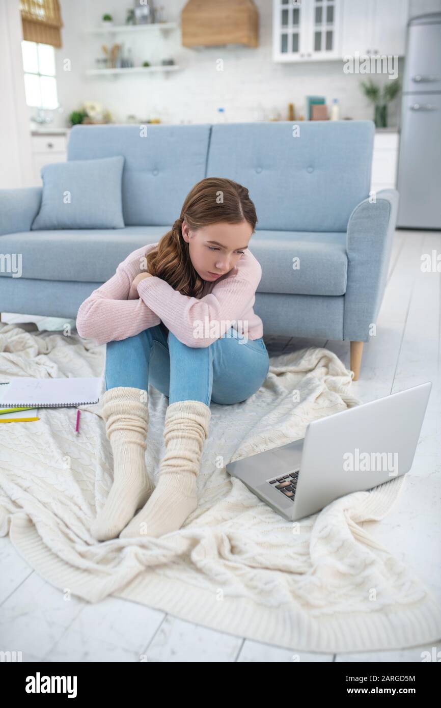 Ragazza triste seduto sul pavimento che guarda un computer portatile. Foto Stock