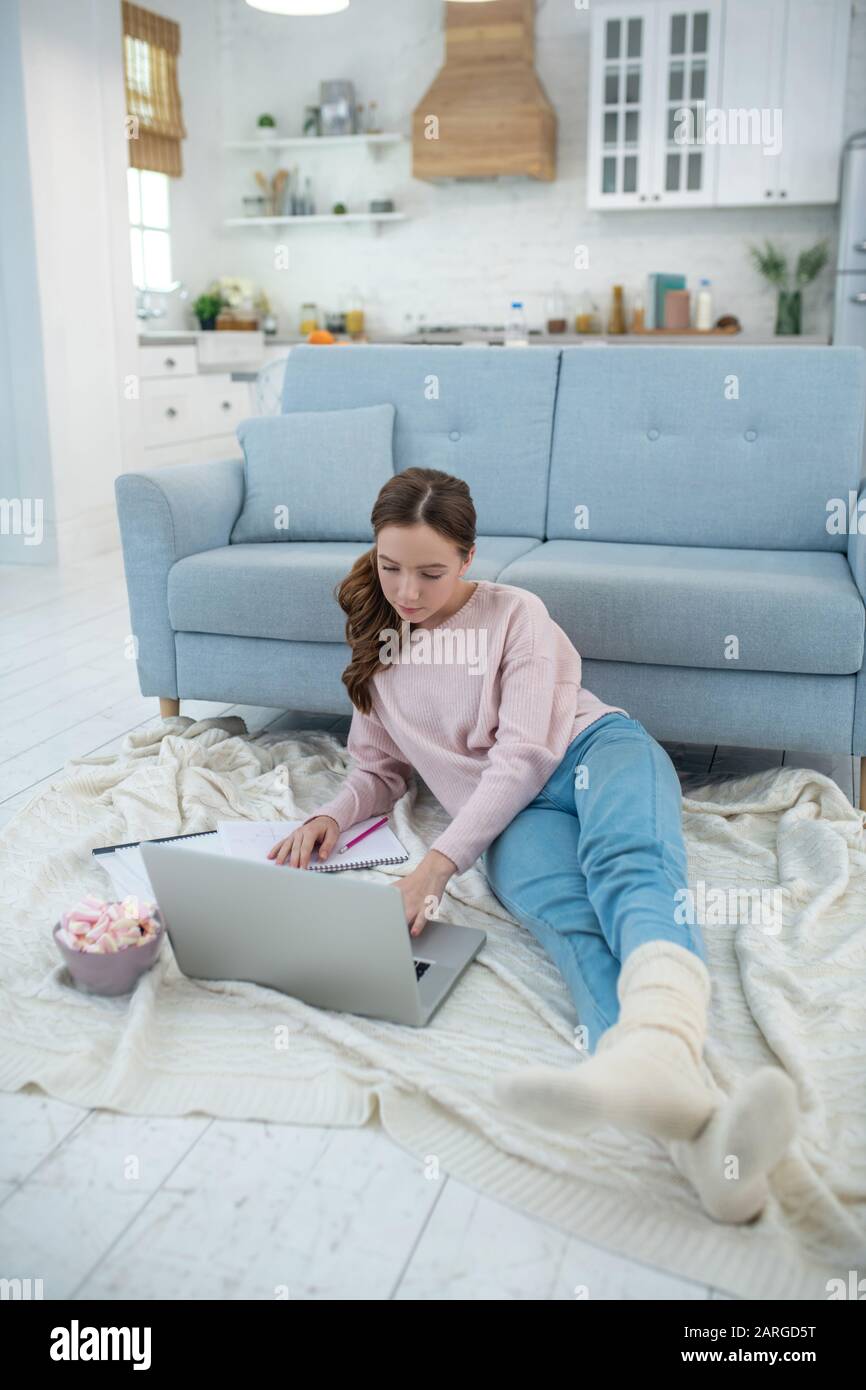 Ragazza sdraiata su plaid sul pavimento guardando il laptop. Foto Stock