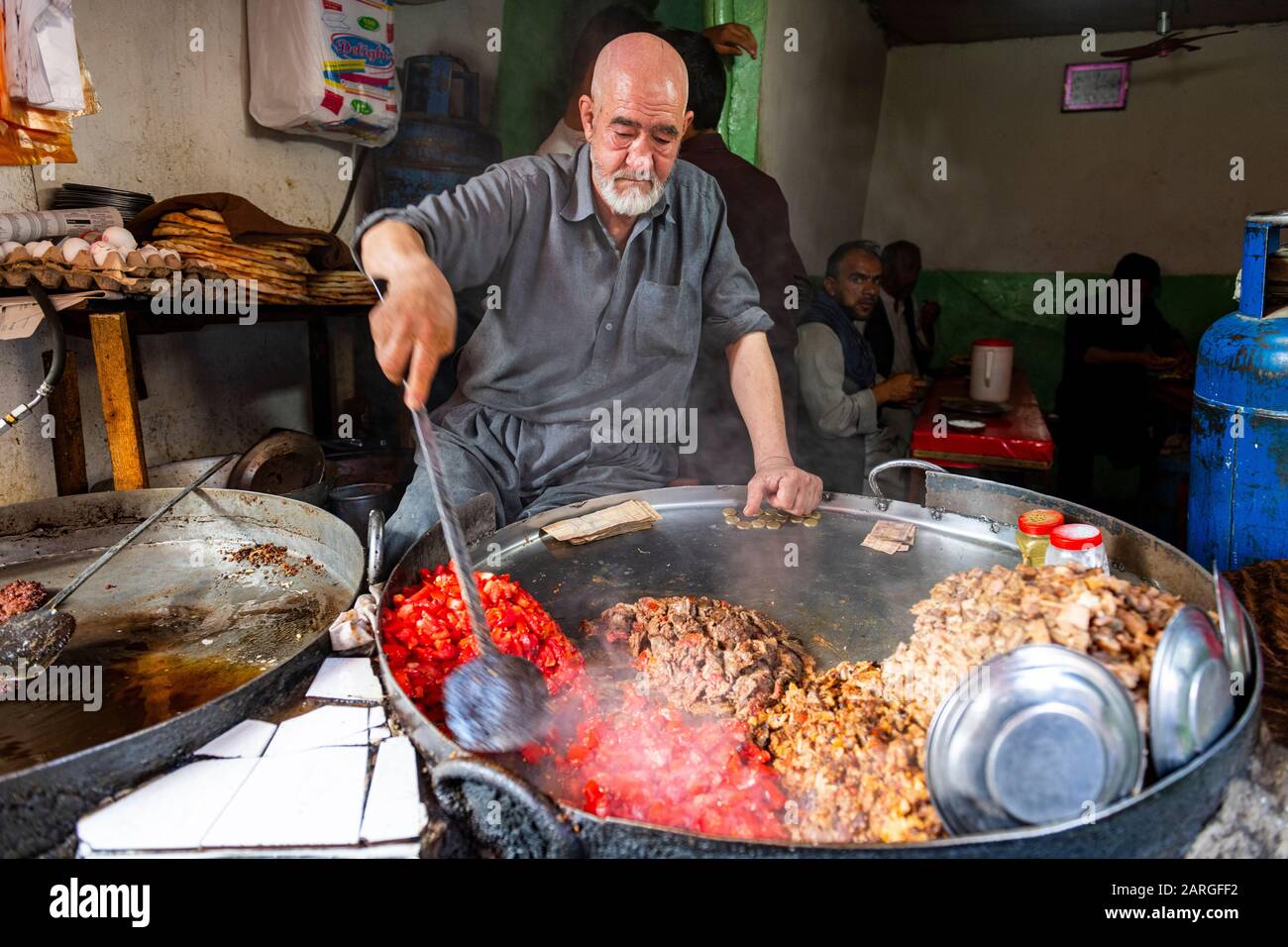 Uomo che cucina cibo in una pentola gigante, Bird Street, Kabul, Afghanistan, Asia Foto Stock