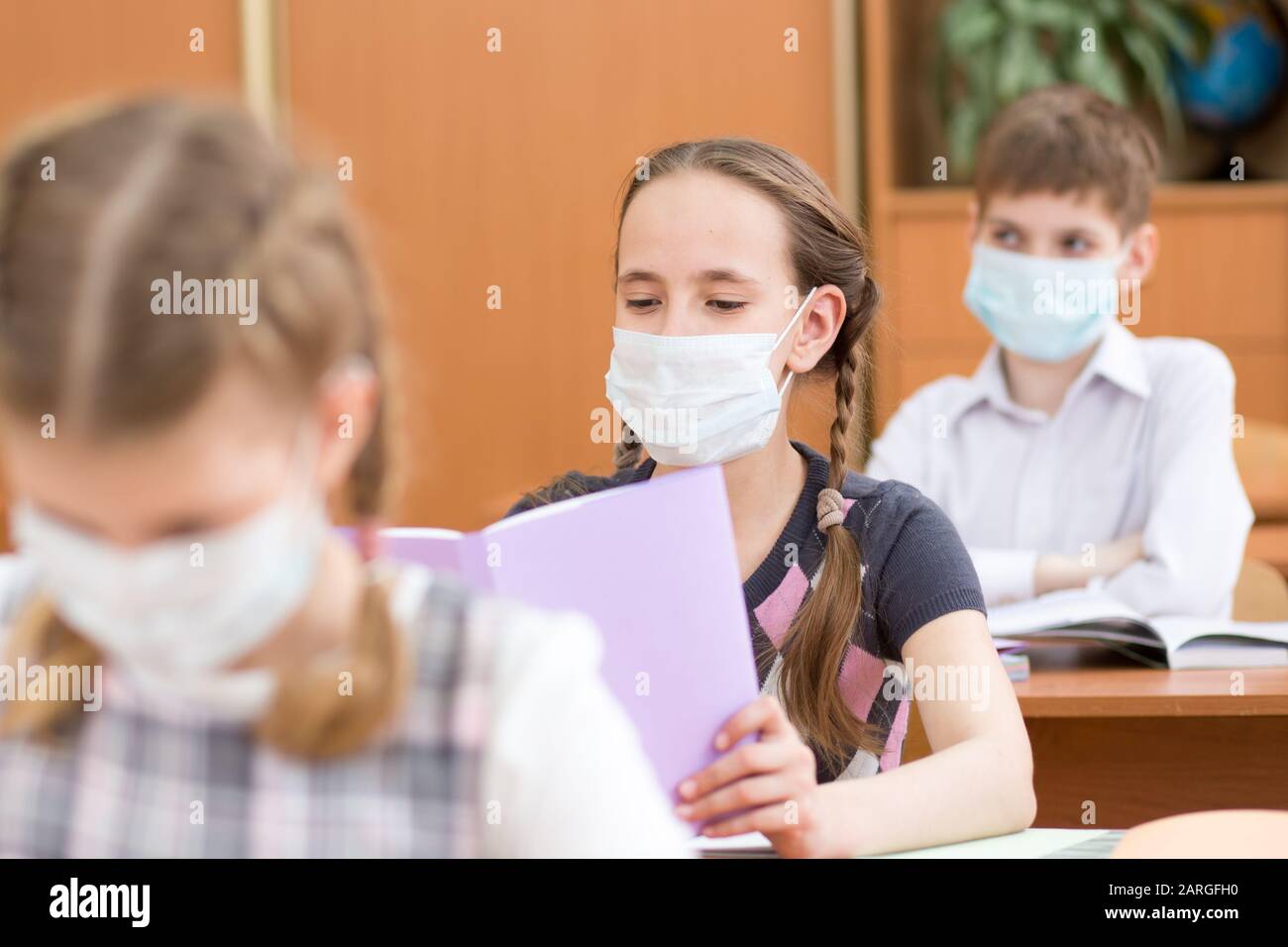 Gli studenti che indossano la maschera di protezione per prevenire il virus durante la lezione in aula a scuola Foto Stock