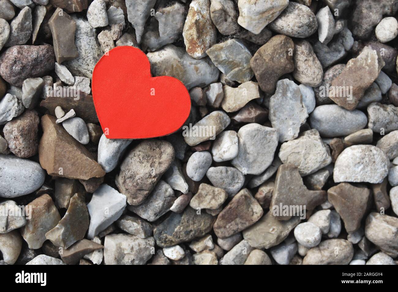 Piccolo cuore di carta rossa su sfondo di pietre grigie Foto Stock