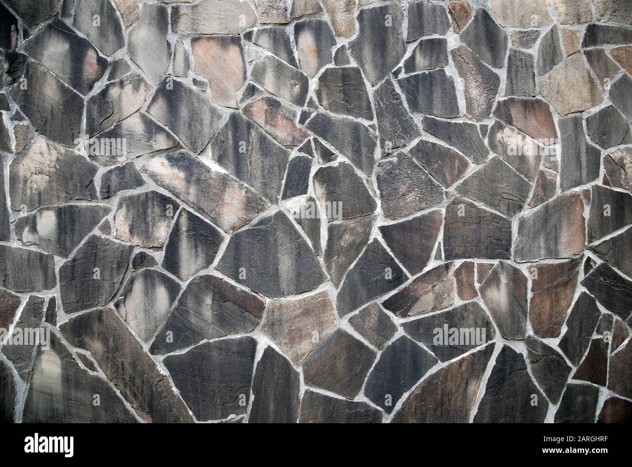 Parete in pietra di ardesia naturale di poligoni irregolari in colori marrone grigio Foto Stock