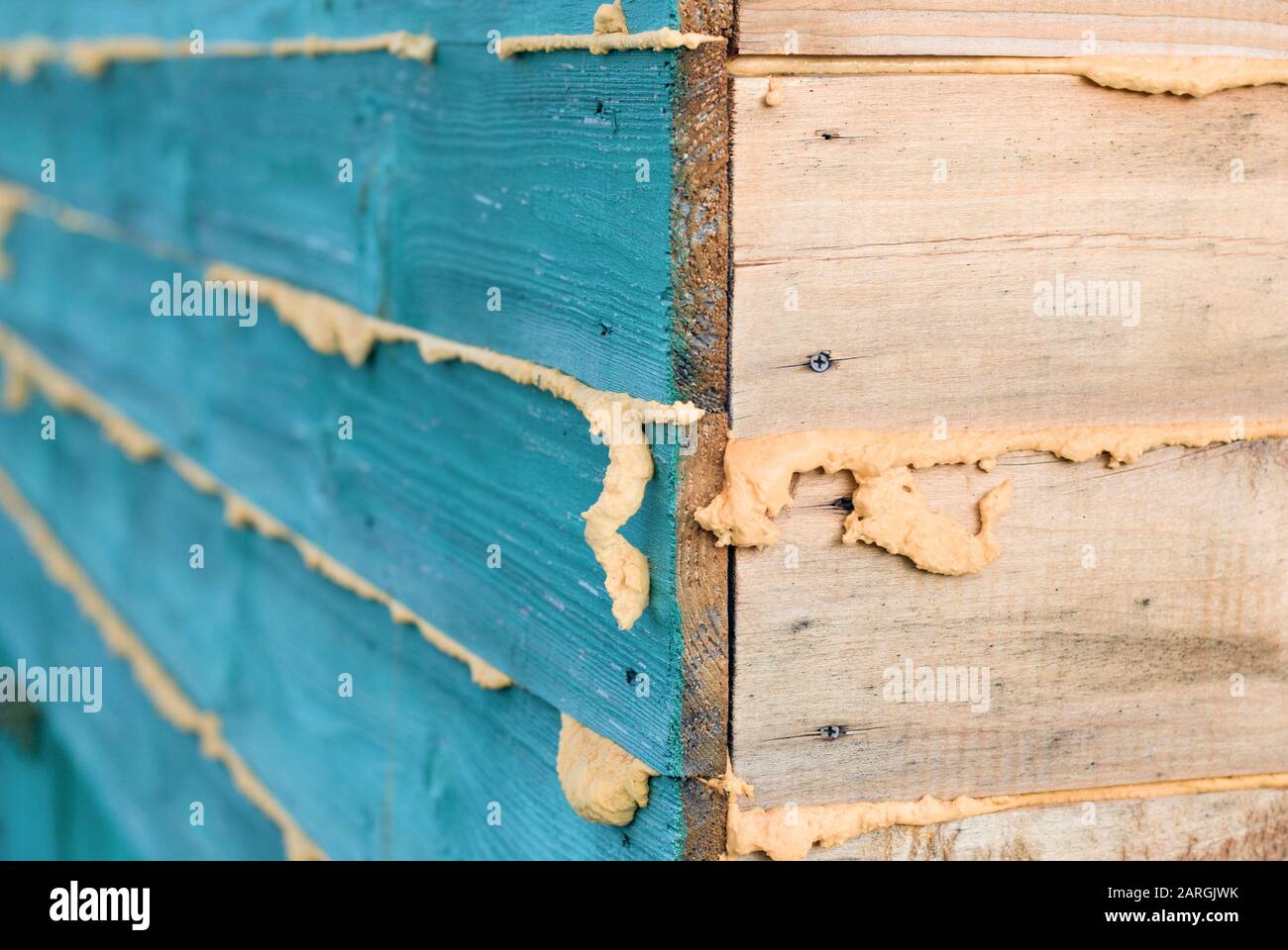 Angolo di casa in legno, cuciture riempite con schiuma di poliuretano per isolamento termico Foto Stock