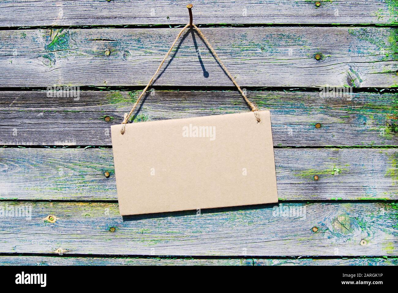 Sfondo in legno naturale, cartoncino marrone vuoto appeso alla corda. Mockup, orizzontale. Foto Stock