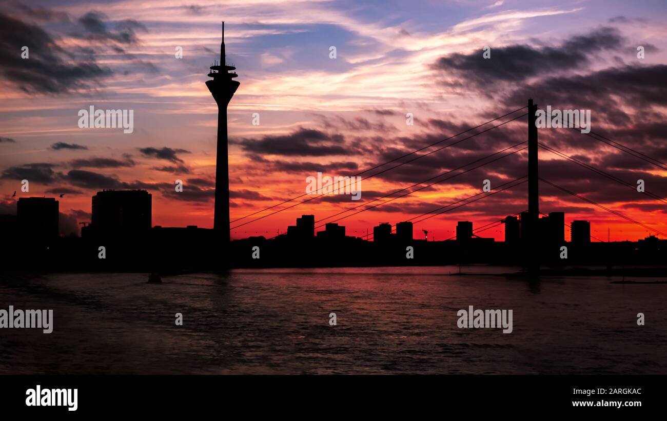 Silhouette nera della torre della televisione di Düsseldorf e del ponte sul Reno al tramonto con bei colori Foto Stock