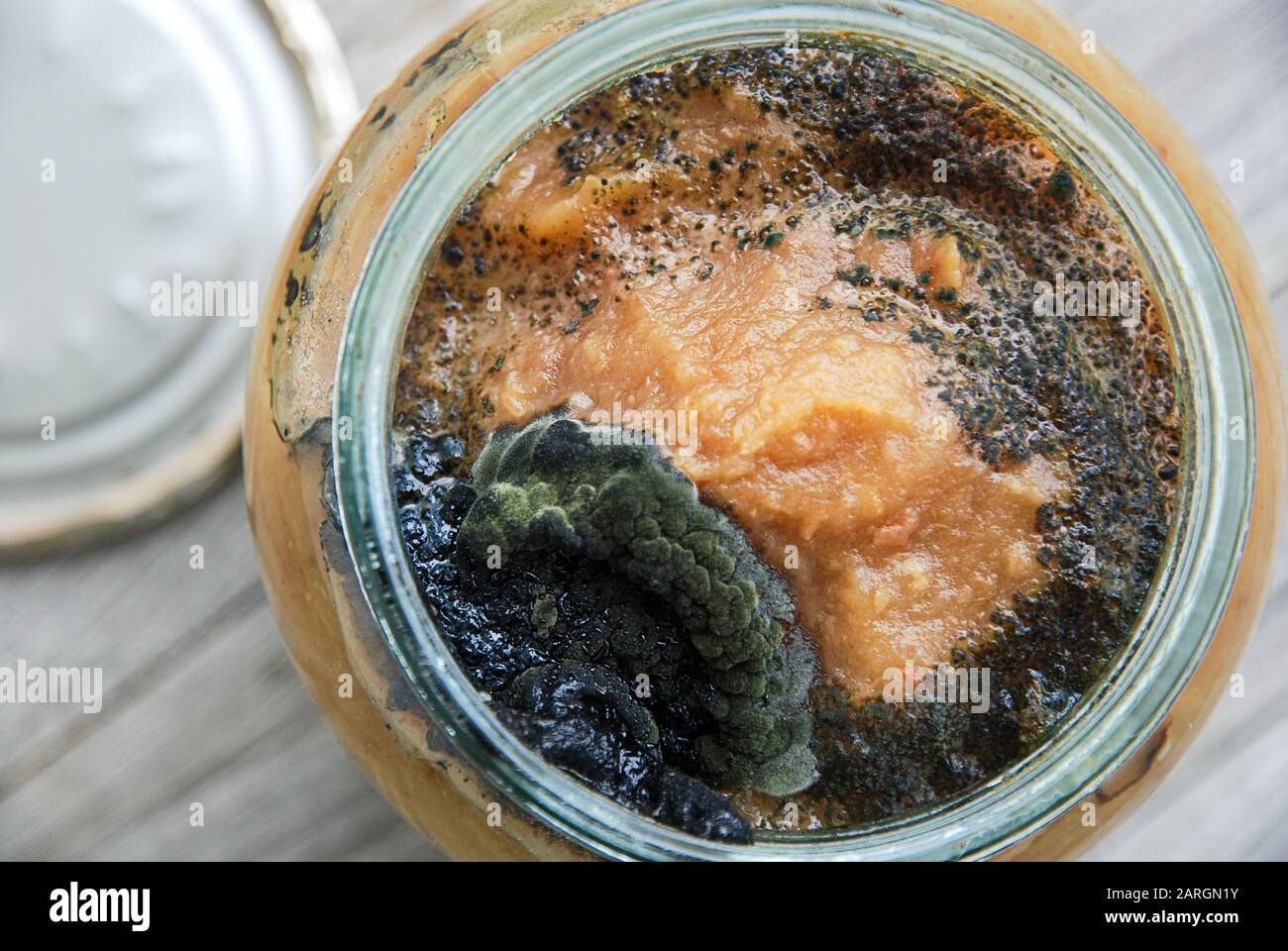 Aprire il vaso di vetro di marmellata di mele fatta in casa con stampo scuro sulla parte superiore. Conservazione impropria di cibo inscatolato domestico. Foto Stock
