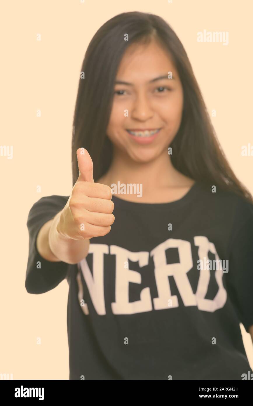 Studio shot di giovani felici Asian teenage nerd ragazza sorridente e dando un pollice alzato con focus sul pollice Foto Stock