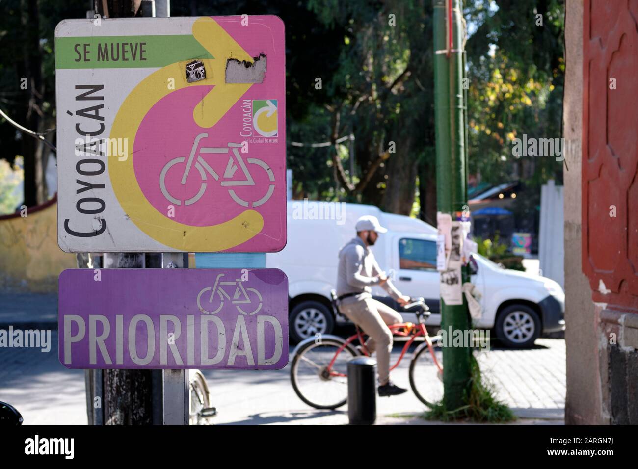 Città Del Messico, Messico. Il ciclismo segno di priorità attraverso il quartiere Coyoacan, con un ciclista a cavallo in background Foto Stock