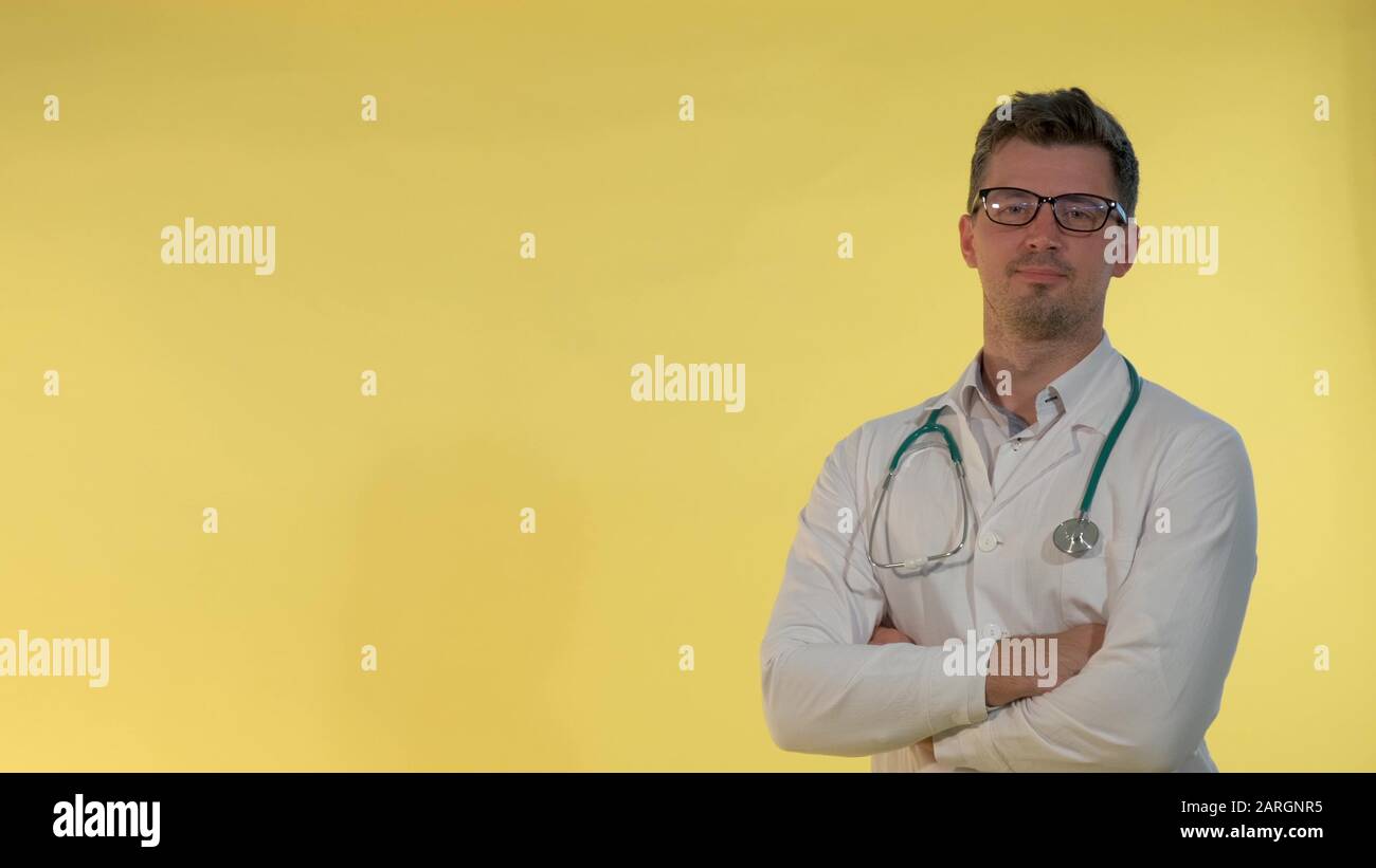 Allegro giovane medico in camice da laboratorio annuendo la testa mostrando che è d'accordo con qualcosa. Lui in occhiali e con stetoscopio sulle spalle. Foto Stock