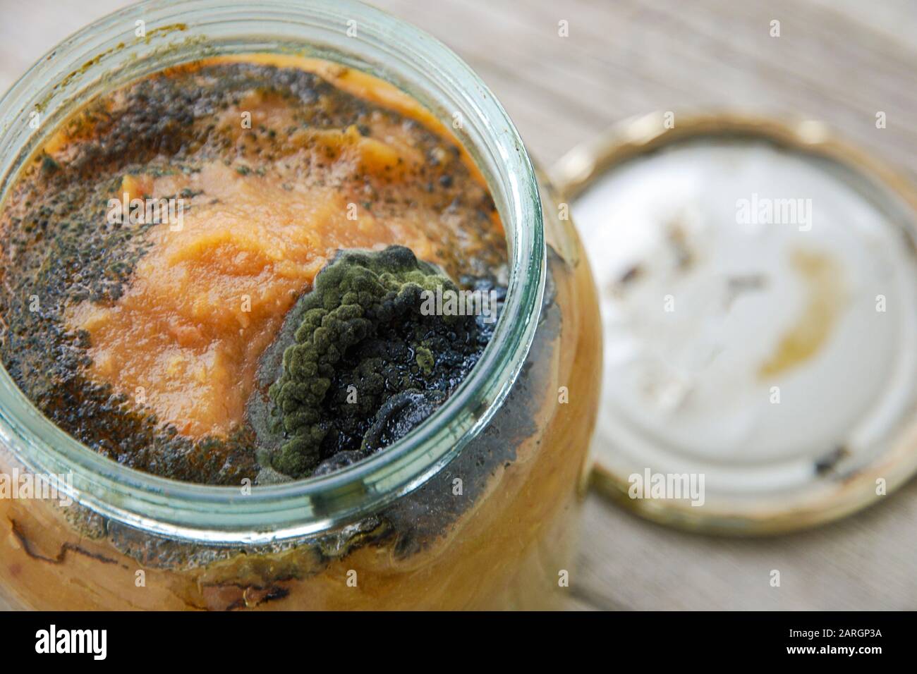 Marmellata di mele fatta in casa rovinata in un vasetto ricoperto di muffa scura. Violazione della tecnologia di cottura. Conservazione impropria di cibo inscatolato domestico. Foto Stock