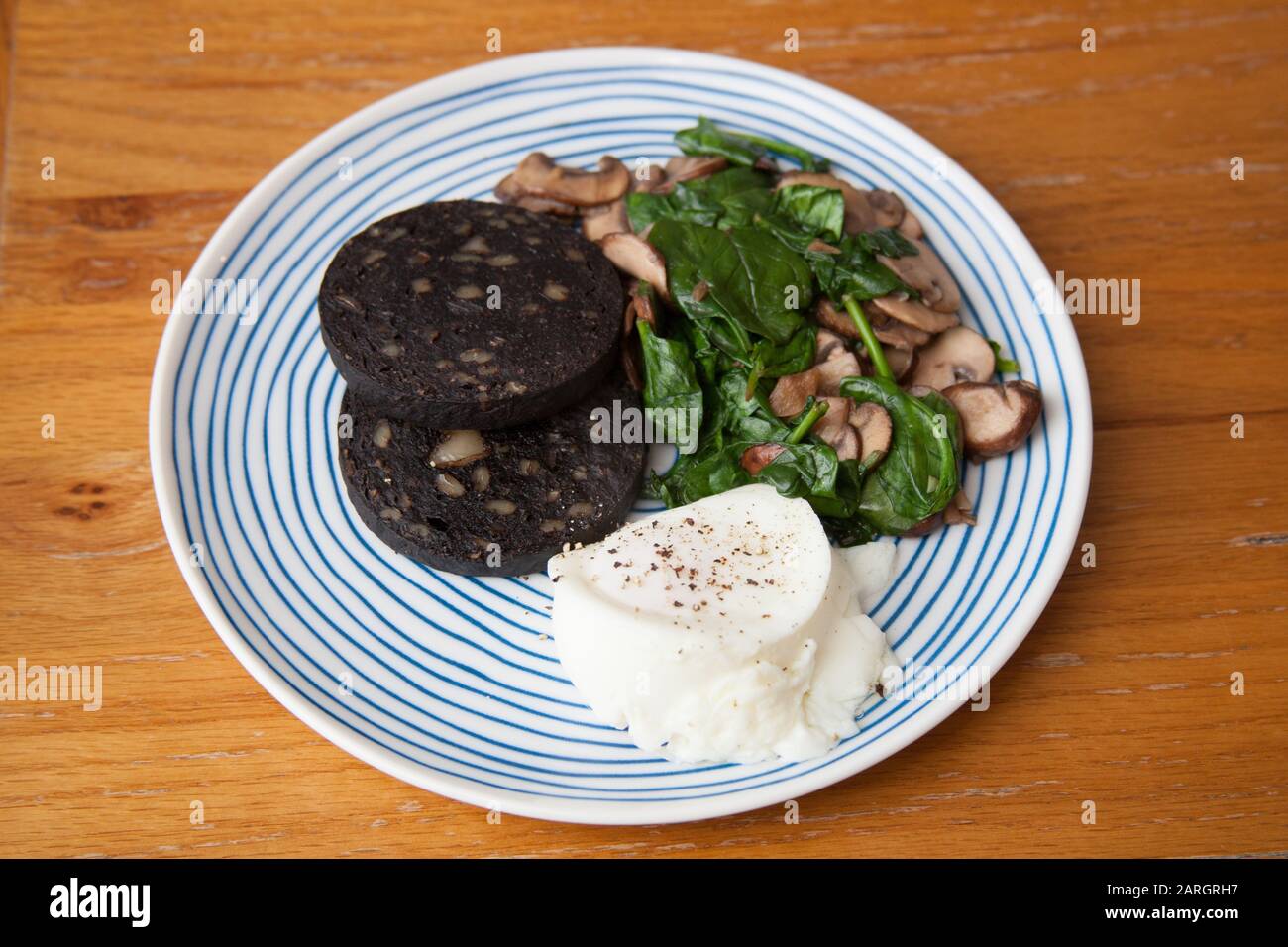 Una colazione con budino nero, uova in camicia, spinaci e funghi Foto Stock