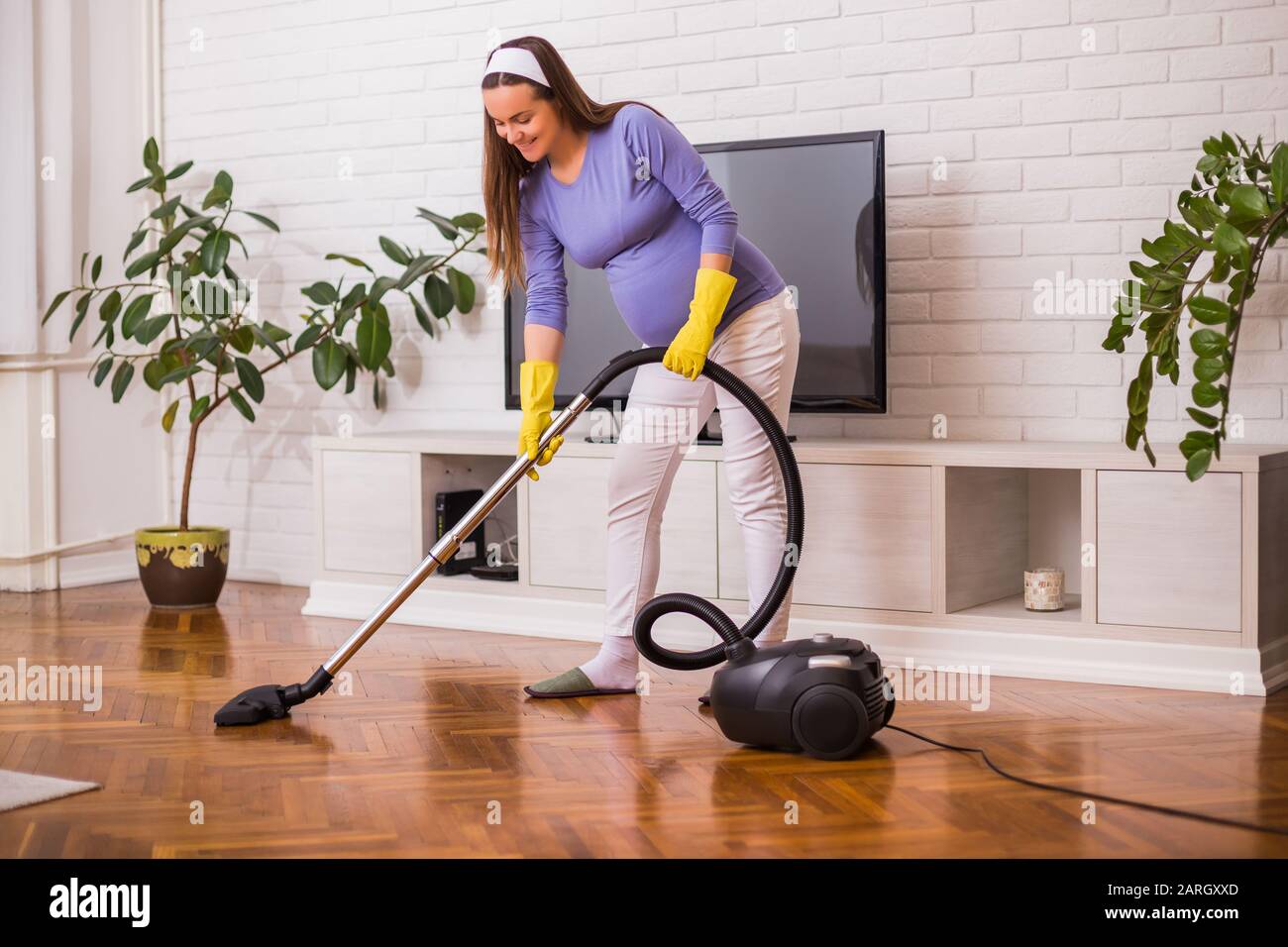 Bella donna incinta ama pulire la sua casa. Foto Stock