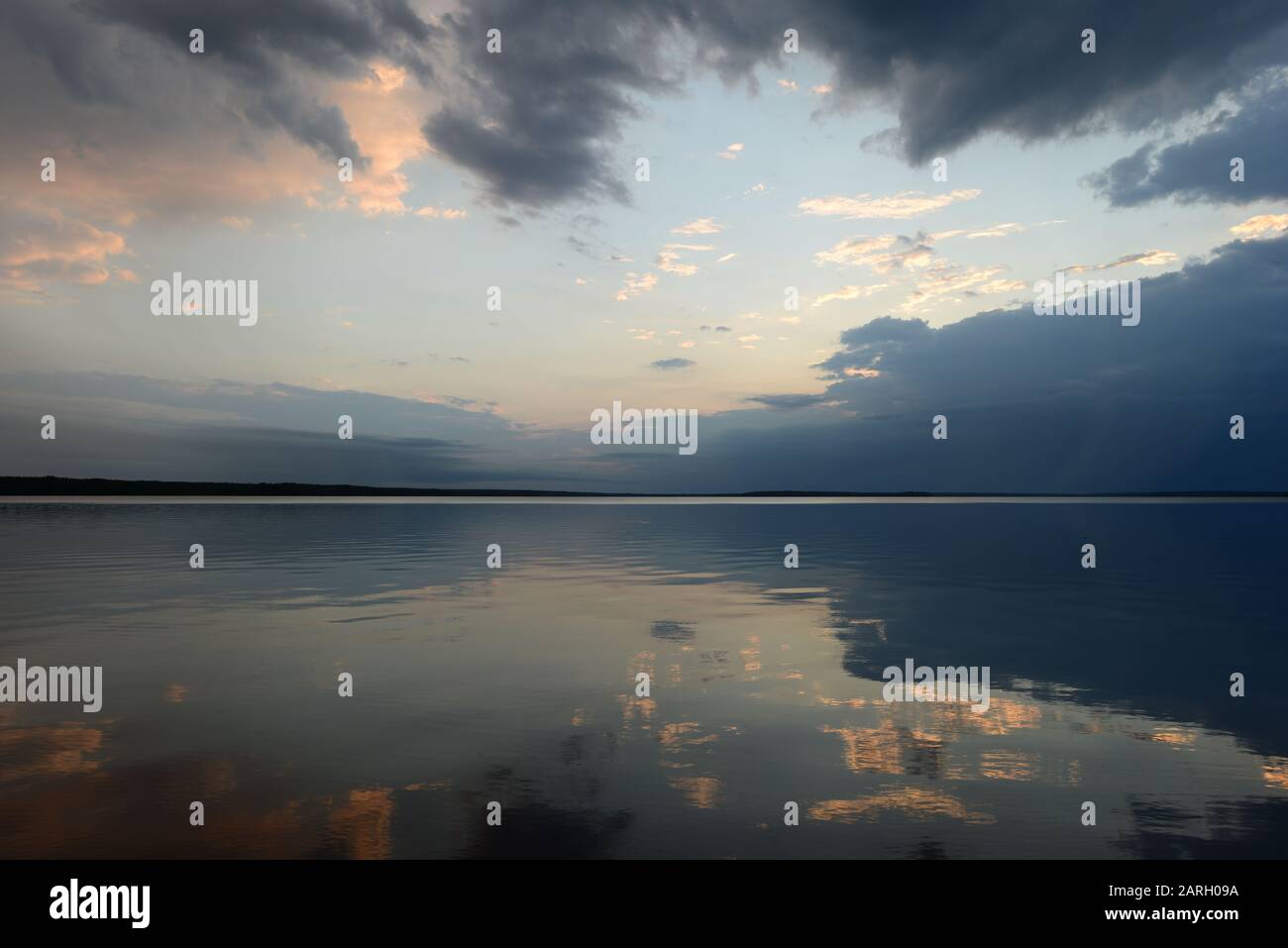 Riflessione del cielo nell'acqua del lago nella calma al tramonto Foto Stock