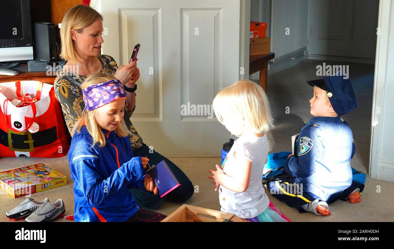 Mamma Con Tre Bambini Che Guardano I Regali Di Natale, Scattare Foto Sulla Fotocamera Del Telefono Foto Stock
