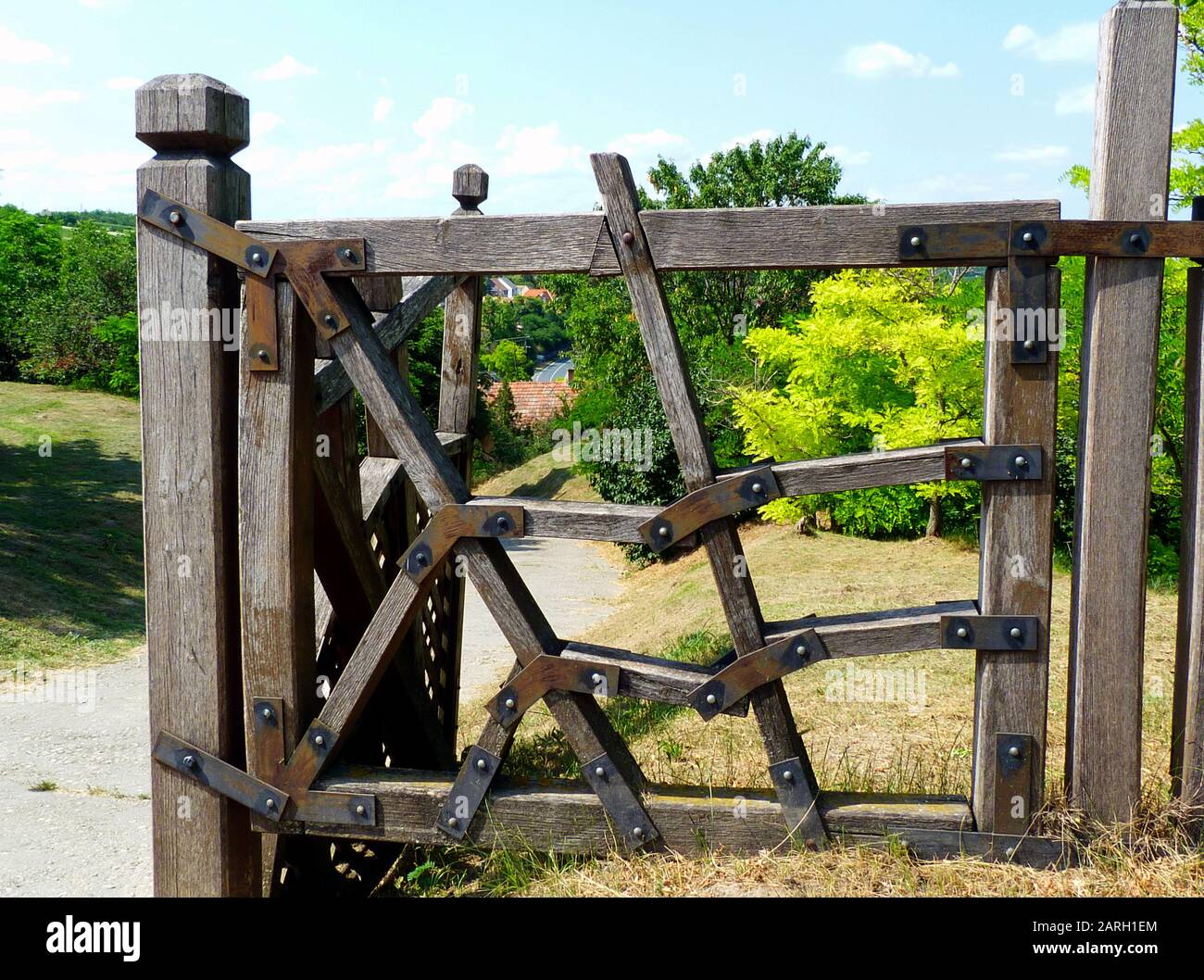 recinzione rustica in legno e porta posta e pannello con piastre di rinforzo in acciaio nero decorativo imbullonato agli elementi di recinzione in legno duro. Foto Stock