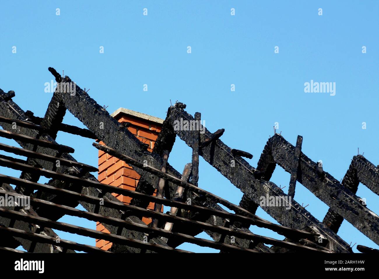 Danneggiato esposti carbonizzati nero bruciato sul tetto di legno struttura dopo la casa di fuoco. fire danneggiato le travi di legno. blue sky. sicurezza antincendio e concetto di assicurazione. Foto Stock