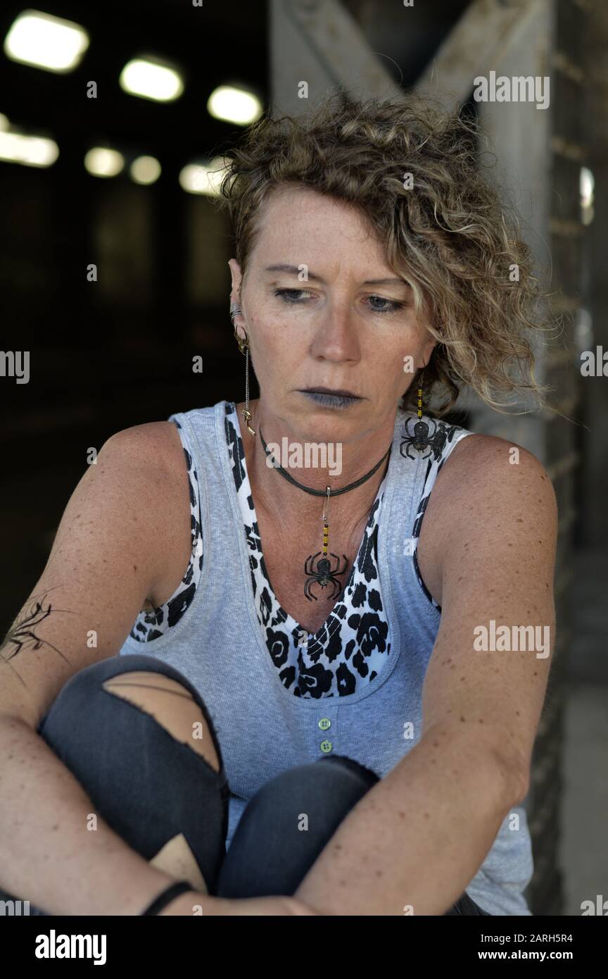 una donna punk matura stressata sta guardando pensieroso verso il basso Foto Stock