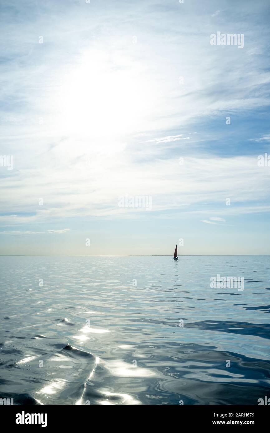 Bellissimo paesaggio estivo. Mare e barca a vela all'orizzonte, contro il cielo blu, in una giornata di sole. Vacanze attive. Foto Stock