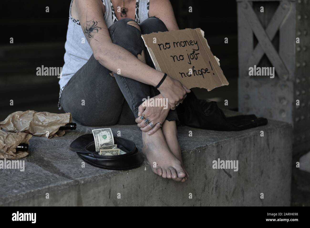 una donna senzatetto punk che implora, con un cartello - nessun denaro, nessun lavoro, nessuna speranza Foto Stock